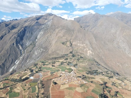 An aerial view of bare mountains rising above a settlement surrounded by fields