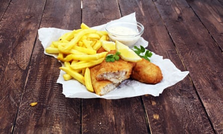 Fish and chips on a wooden table in paper