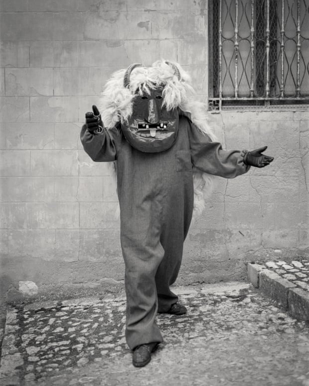 Man with outstretched arms wearing huge devil mask