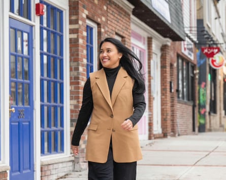 A young woman walking down a sidewalk and smiling.
