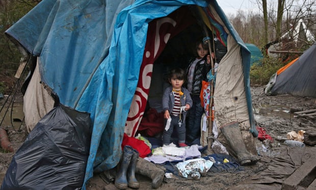 Children stand inside a tent at a refugee camp in northern France