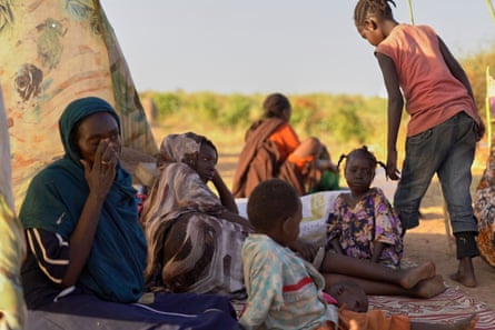 Woman with several young children sat on the ground at a displacement camp.