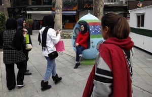 People take pictures of a woman sitting in a large egg-shaped seat