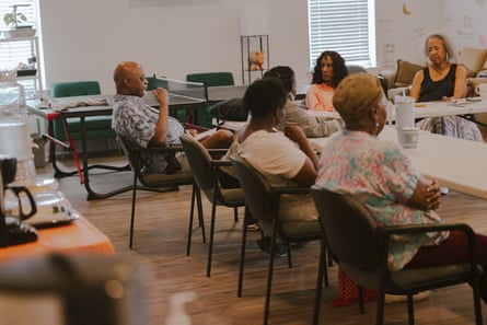 a group of people sitting in chairs around a rectangular table