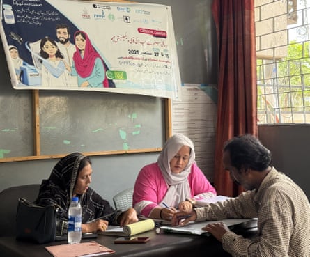 Two women and a man sit at a desk in an office