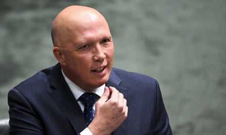 Bald man (Peter Dutton) smiles as he talks in Parliament wearing a dark suit and tie