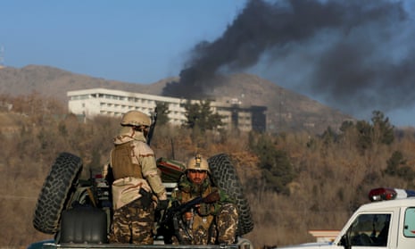 Security forces keep watch as smoke rises from the Intercontinental Hotel in Kabul