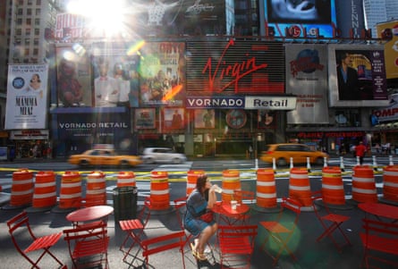 A woman enjoys her morning coffee in the middle of Broadway in Times Square after it was closed to cars.