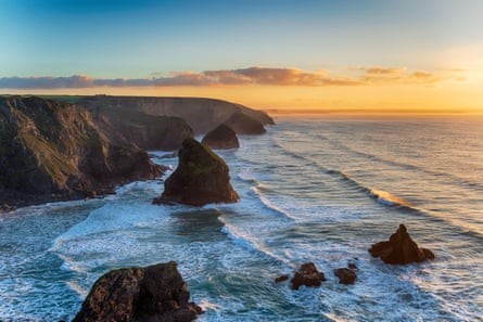 The sun sets over the sea with rocks, sea stacks and headlands
