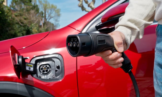 Man holding an electric plug-in car charger outdoors