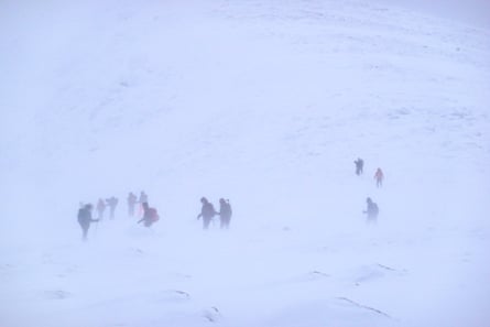 About 12 climbers partly obscured by swirling snow