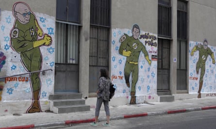 A woman looks at a painted mural of three men portrayed as superheroes