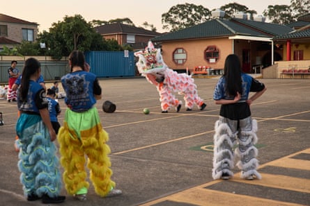 Dancers watch a pink lion dance in the car park