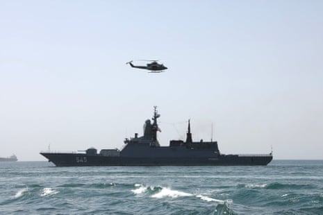 A warship at sea with a helicopter overhead.