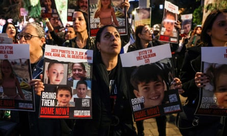 A woman holds portraits of hostages, including children of the Almog-Goldstein family, in November 2023