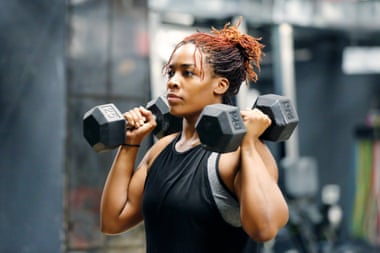 Fit, young African American woman working out with hand weights in a fitness gym.Wasit up image of a fit, young African American woman working out with hand weights in a fitness gym.