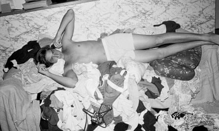Young man wearing only boxer shorts lying on a floor covered with clothes