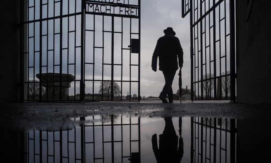 A man walks through the gate of the Sachsenhausen Nazi death camp, where the man is alleged to have been a guard. The phrase reads ‘work sets you free’.