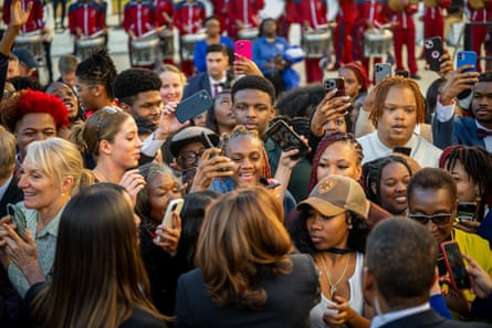 crowd of young people gather around harris, seen from the back