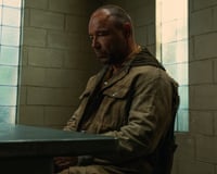 Stephen Graham sits quietly in a brick-walled room