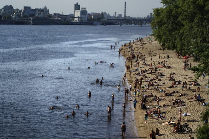 In some areas of Ukraine life continues as normal, as bathers spend a summer Sunday afternoon along a beach on the Dnieper River in Kyiv.