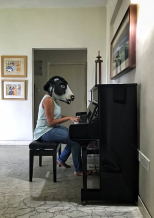 A woman in a cow mask plays the piano.