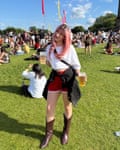 Leah at festival holding drinks, wearing a long pink wig