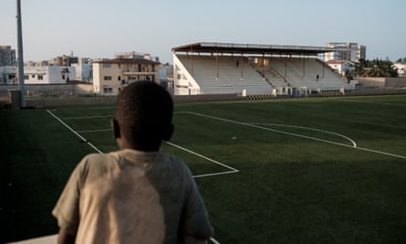 Un ragazzo guarda il campo di uno stadio di calcio a Dakar.
