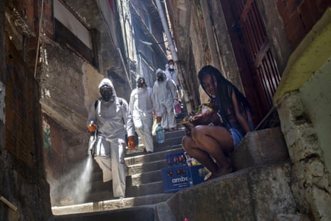 Volunteers spray disinfectant in an alley to help contain the spread of the new coronavirus, at the Santa Marta slum in Rio de Janeiro, Brazil, Saturday, 28 November, 2020.