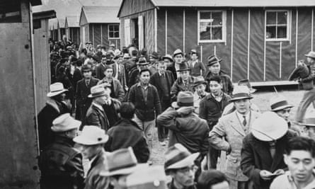 Japanese American detainees walk among the accommodation cabins of the Manzanar War Relocation Center in California on 23 March 1942.