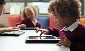 School children working on digital tablets at the library