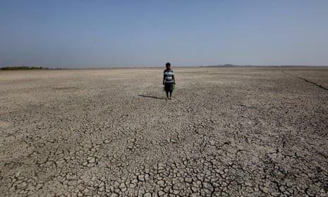An Indian man searching for drinking water walks on a dried-up portion of Bhopal's Upper Lake, commonly known as Bhopal Taal or Bhojtal, after it shrunk as a water crisis continues during the hot summer