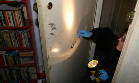 A forensic police officer dusts a door for fingerprints after a break-in at a flat.