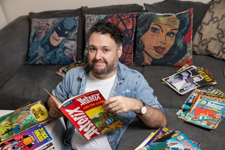 A man sitting on the floor holding an Asterix comic