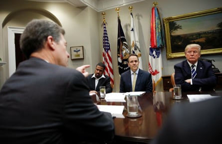 four men in suits in a room with flags
