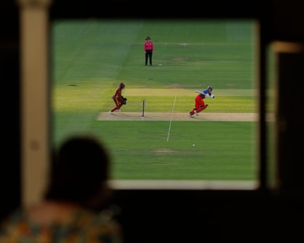 England’s captain Charlie Dean plays a shot as a scorer watches through a window in the scoreboard.