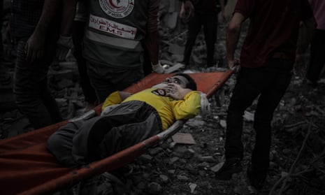 An injured man is carried from the rubble of a building destroyed by an Israeli attacks on Al-Maghazi refugee camp in Deir Al Balah.