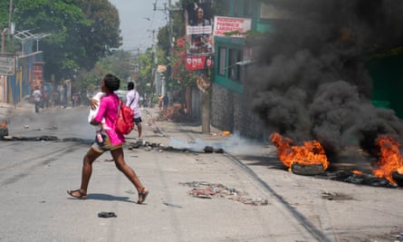 A woman carrying a child runs after gunshots were heard in Port-au-Prince, Haiti, on 20 March 2024.