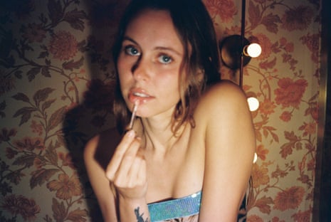 A woman poses while putting lip gloss on