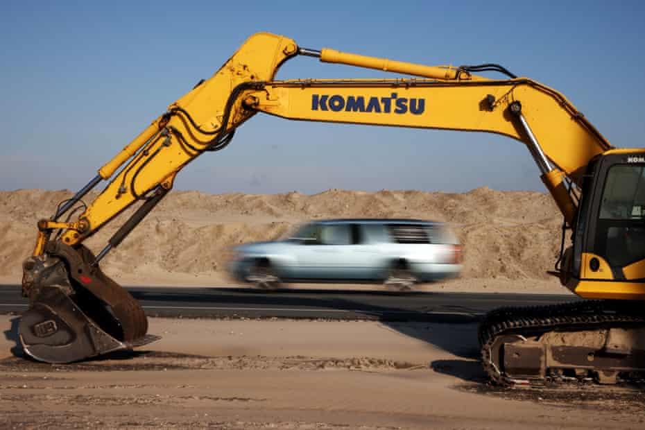 An excavator rests in the sand along Highway 12.