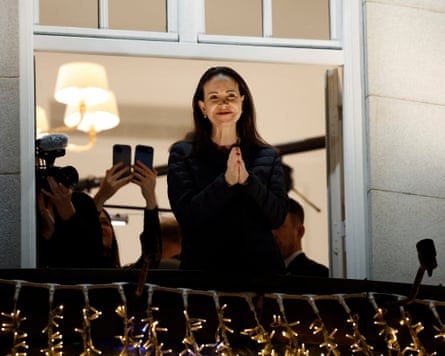 Machado stands on a balcony with hands clasped