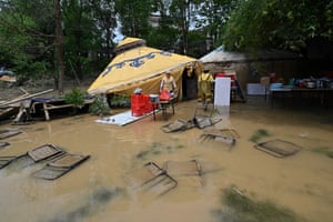 Chairs are submerged as workers collect items after torrential rains flooded the area in Shatang village in Qingyuan, China