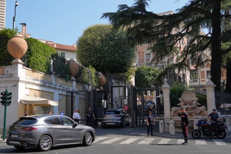 A motorcade outside the US embassy in Rome where four guards are stood near the gates.