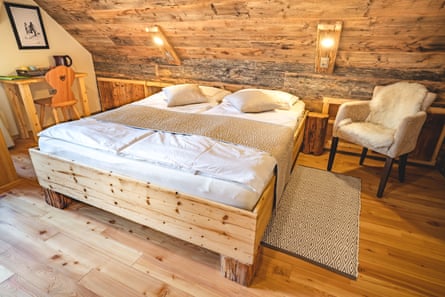 Double bed and chair in wooden-walled room at Senkova Domačija