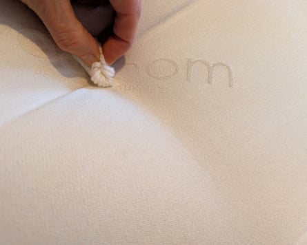 A closeup of a hand pulling the tufting on a mattress