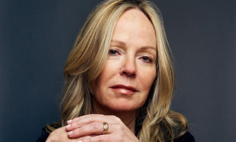 Dani Shapiro, with long, blonde hair, looking at the camera, with her hands folded beneath her chin