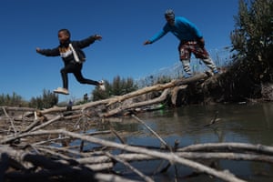 A child jumps from a makeshift bridge made of gathered wood