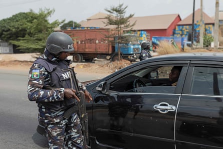 A Nigerian police officer stops a car at a security checkpoint in Awka, Nigeria, on 26 February, following the Nigeria presidential and general election.