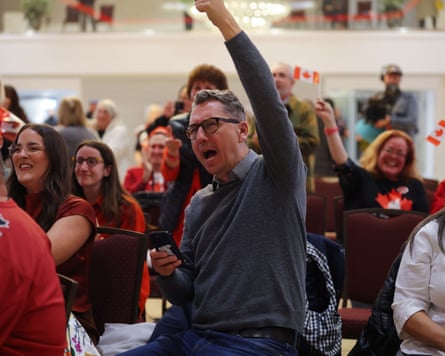 A man in a crowd raises an arm and cheers in celebration