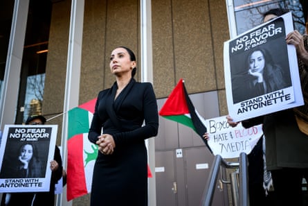 Antoinette Lattouf stands outside court wearing a black tailored outfit.